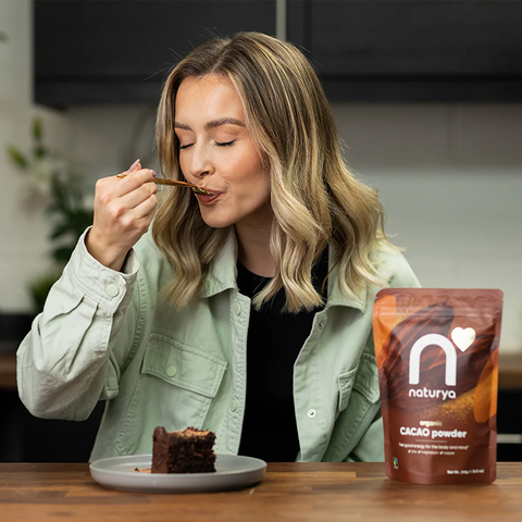 woman eating chocolate cake next to bag of cacao powder