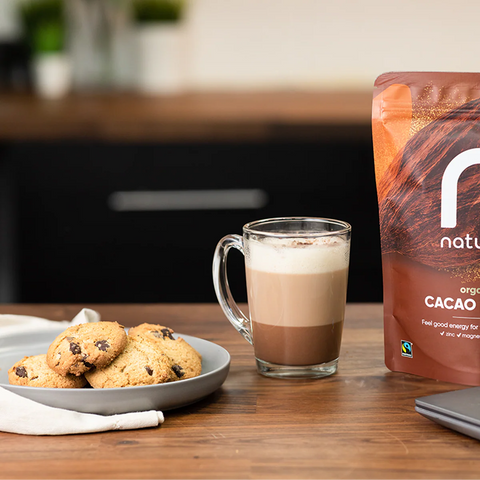 bag of cacao powder next to coffee and cookies on wooden table