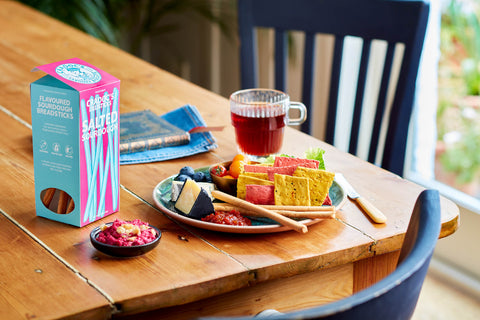 Wooden table with a plate of food, a box of breadsticks, and a glass of juice.