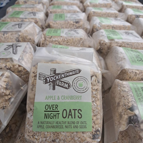A front-facing bag of Yockenthwaite Farm Apple & Cranberry Over Night Oats, with multiple identical bags arranged in rows in the background.