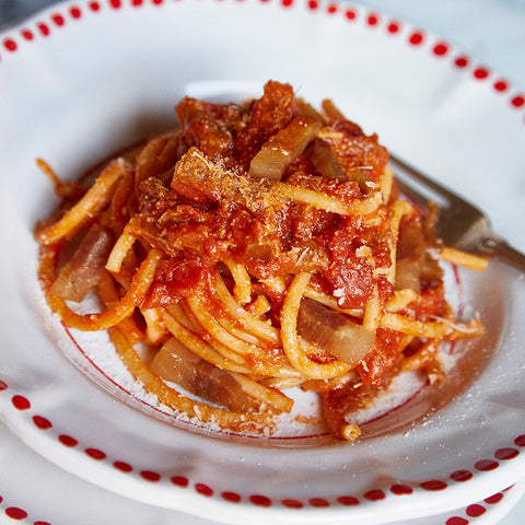 bowl of pasta with red sauce in a white bowl with red dots