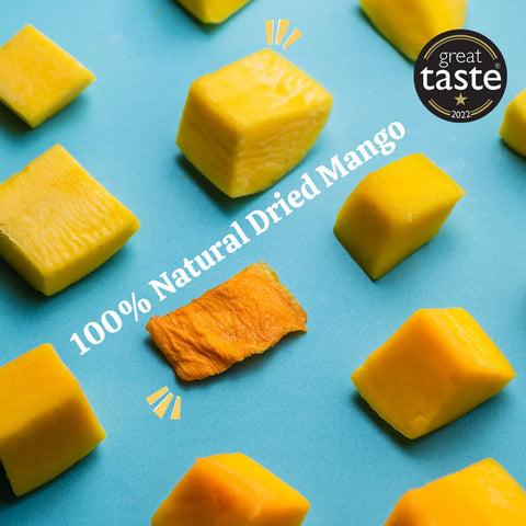 Several cubed pieces of yellow mango and one dried mango slice arranged on a bright blue background, with white text reading '100% Natural Dried Mango' and a circular 'great taste 2021' badge in the top right.