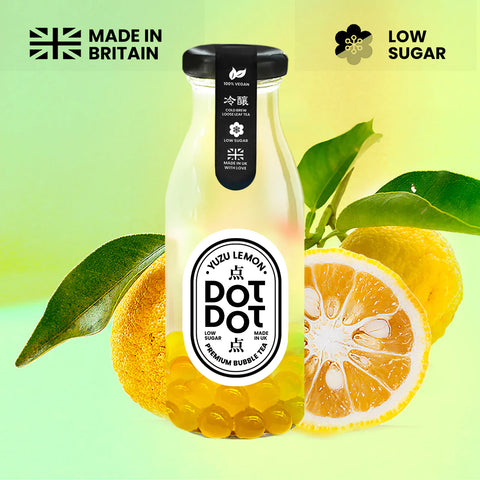Bottle of DOT DOT Kuzu Lemon bubble tea with lemons and leaves on a green background, featuring 'Made in Britain' and 'Low Sugar' labels.