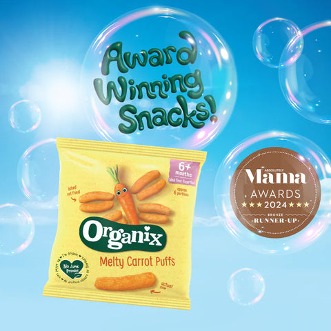 Organix Melty Carrot Puffs snack bag shown against a bright blue background with floating bubbles. The yellow bag features carrot illustrations and the Organix logo, with award callouts including 'Award Winning Snacks!' and a Mama Awards 2024 badge.