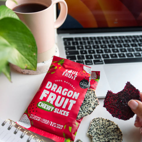 Dragon fruit chewy slices with a red package on a desk with a laptop and coffee.
