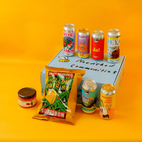 Assorted beer cans and a packet of crisps on a hamper box with a yellow background