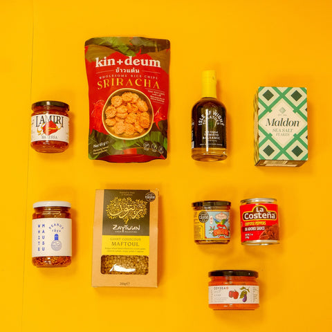 Collection of various food products including jars and packets on a yellow background