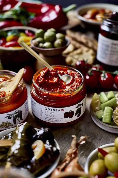 jar of spicy ajvar with spoon in it surrounded by food