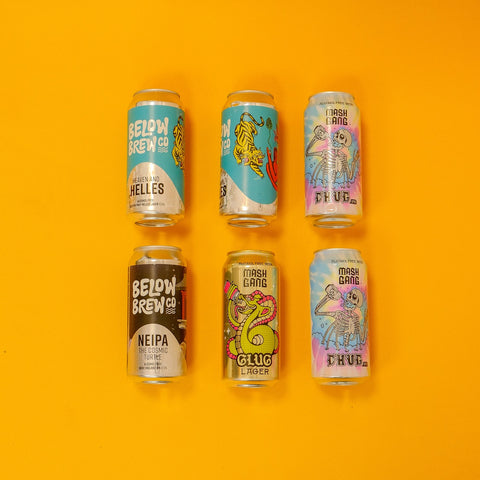 Six alcohol free beer cans with colourful labels on an orange background