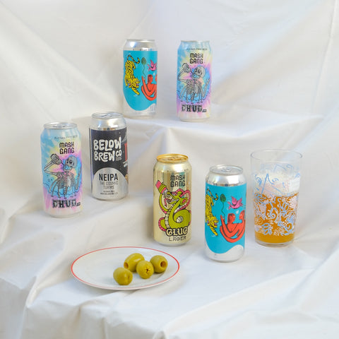 Assorted alc free beer cans with colorful labels on a white fabric background