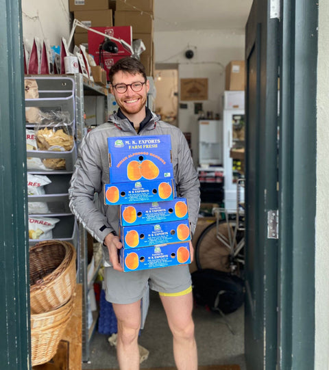 Customer holding cases of alphonso mangoes