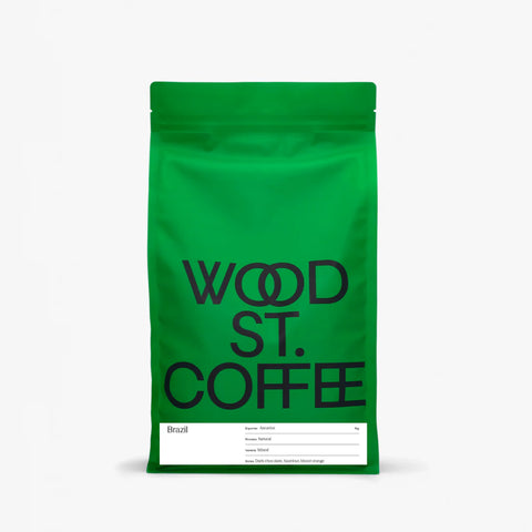 A bright green stand-up coffee bag with large black text reading 'WOOD ST. COFFEE' and a white label at the bottom, photographed on a clean white background.