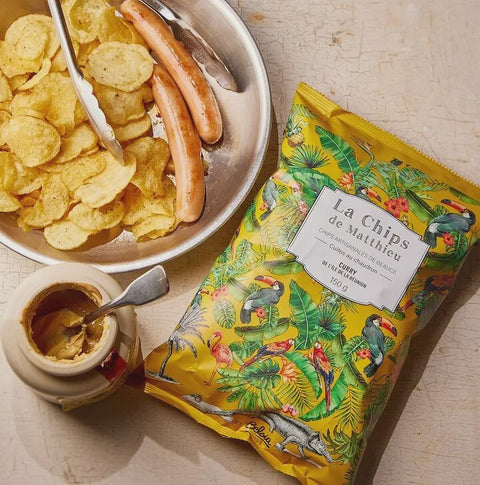 Picture of belsia crisps with a pot of mustard and plate of sausages and crisps
