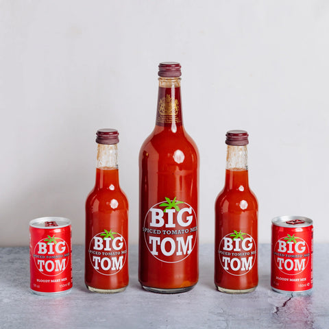 Collection of Big Tom tomato sauce bottles and cans on a gray surface with a white background