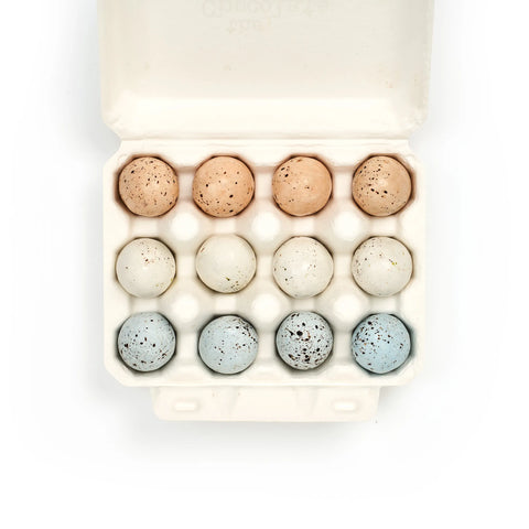 Egg carton with speckled eggs on a white background