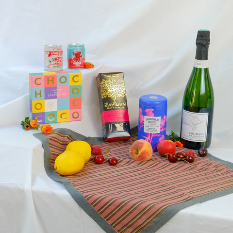 Assorted items including a bottle of cremant, biscuits, dates and cocktails on a white surface.