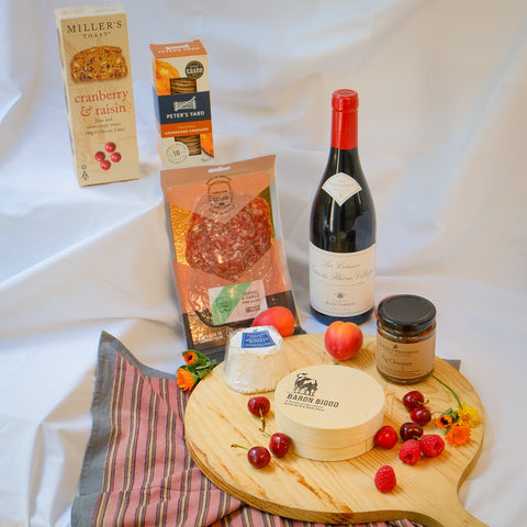 Assorted food items including cheese, crackers, and a bottle of wine on a white surface.