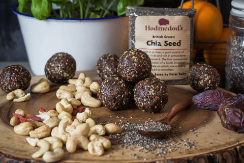 Chocolate truffles with nuts and chia seeds on a wooden board, Hodmedod's Chia Seed package in the background.