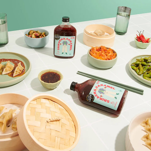 Table with food and bottles of sauce against a light green background