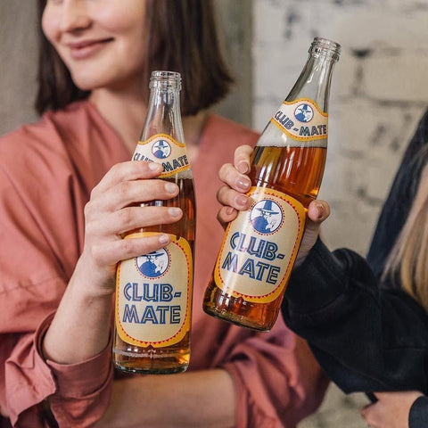 people cheering with a bottles of club mate 