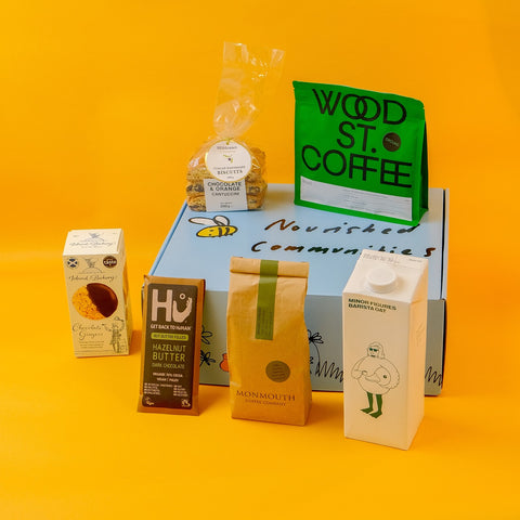 Collection of food products including coffee, chocolate, and Monmouth chocolate on a hamper box with a yellow background