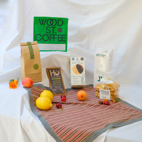 Assorted food items and coffee packages on a tablecloth with a white background
