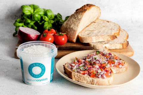 Furness Salts sea salt crystals with a plate of bruschetta and bread slices on a light background