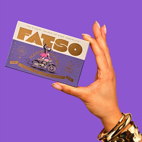 Hand holding a box of FATSO chocolate against a purple background
