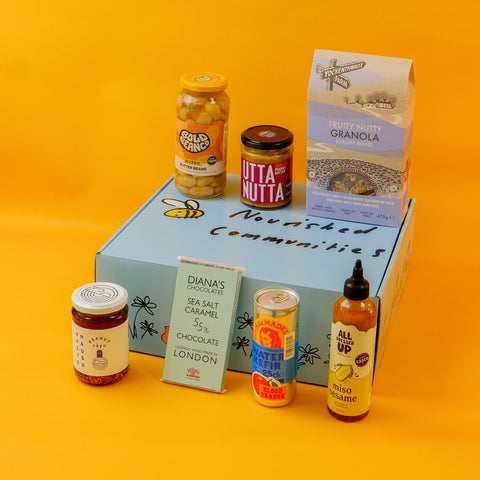 Collection of female owned food products including jars, a box, and a bottle on an orange background