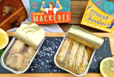 tins of mackerel and cornish sardines on wood surface with salt and lemons surrounding 