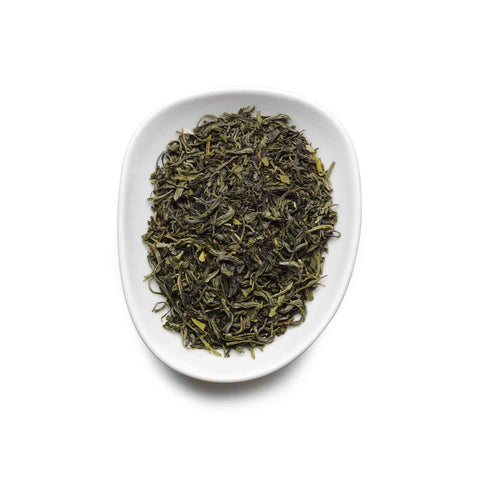 Dry green tea leaves on a white plate with a white background