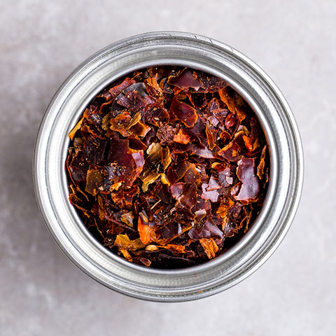 close up of chili flakes in container on grey surface