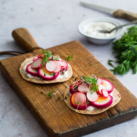 sourdough crispbread with greens and beets on a wooden cutting board