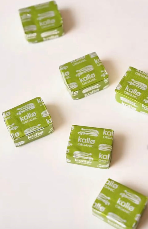 Five small square packages of Kallo Organic cubes arranged on a plain white surface, each wrapped in light green paper with white printed branding.