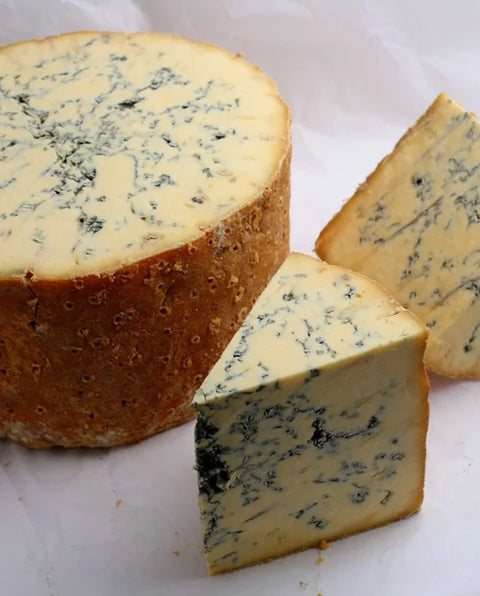 Blue cheese wedge and round on a white surface