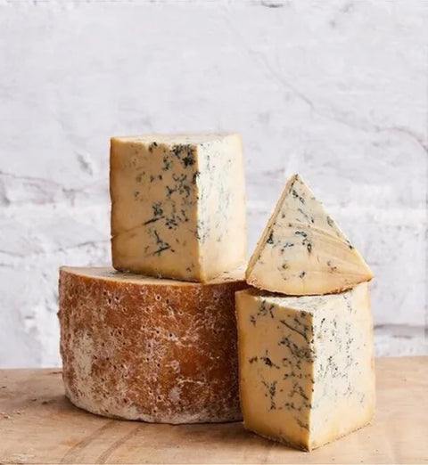 Three types of blue cheese on a wooden board with a marble background