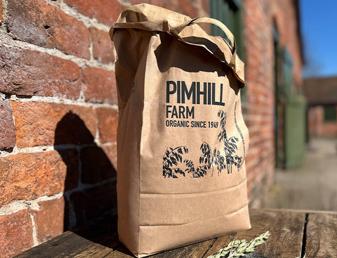 Brown paper bag with 'Pimhill Farm' branding against a brick wall.