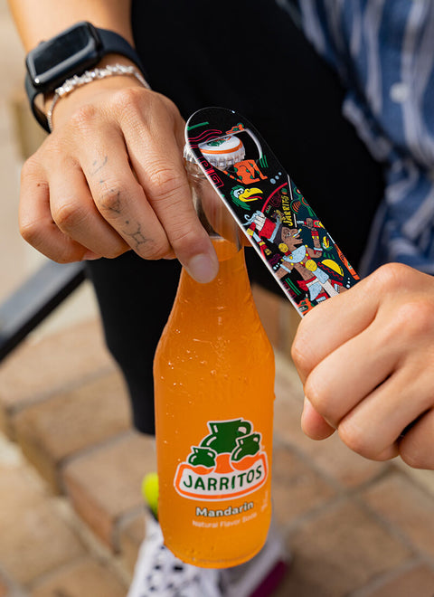 hand holding bottle of jarritos using can opener in other hand