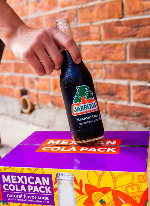 hand holding bottle of jarritos on a box