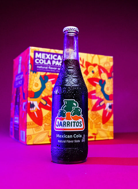 bottle of jarritos on purple background with cola pack box