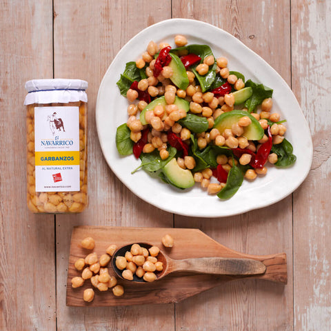 Chickpea salad with a jar of Navarrico chickpeas on a wooden surface