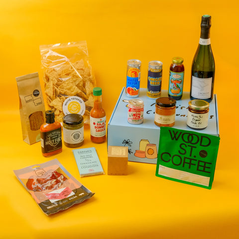 Assorted food and drink products from London on a hamper box with a yellow background