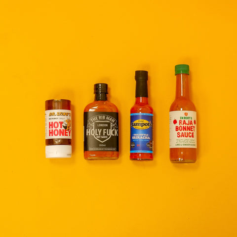 Four hot sauce bottles on a yellow background