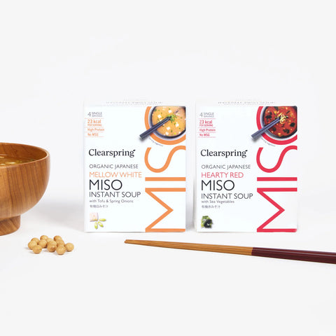 Clearspring Miso instant soup packages with a wooden bowl and beans on a white background