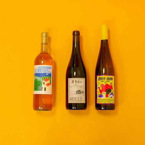 Three wine bottles with colorful labels on a yellow background