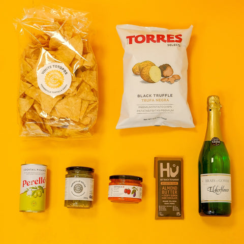 Assorted snacks and a bottle of champagne on a yellow background
