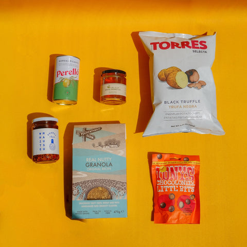 Torres Crisp pack, perello olive can, granola box, jar of sauce and honey on yellow background