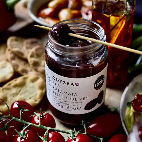 jar of olives surrounded by tomatoes and crackers