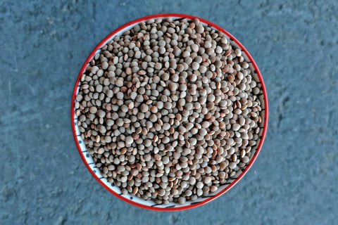 Close-up of a bowl filled with small seeds on a textured blue background