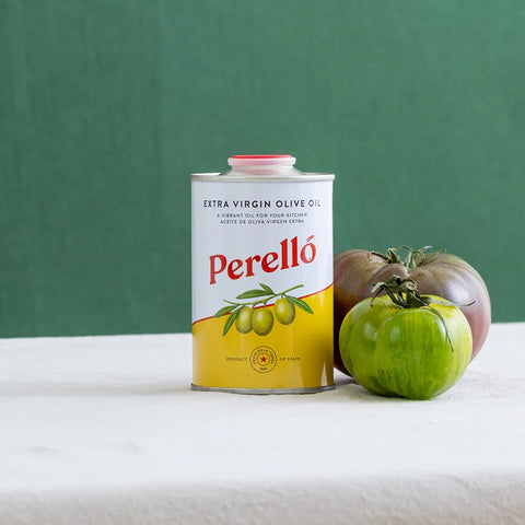 Perello extra virgin olive oil can with tomatoes on a white surface and green background
